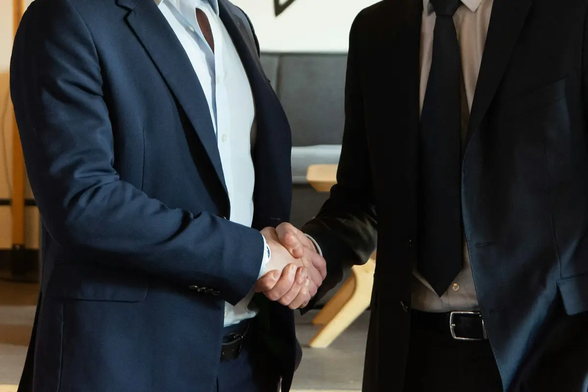 Dois homens de terno apertando as mãos ao fechar um acordo