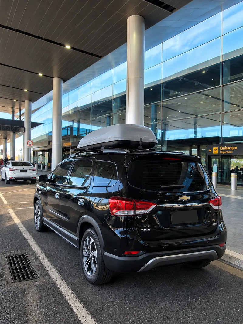 Black Chevrolet Spin with a roof box, at an airport departure area